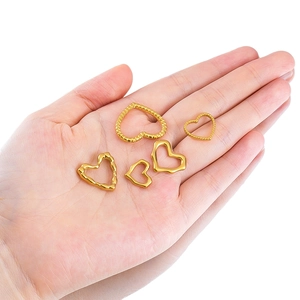 Golden heart pendants in diverse textures held in hand for jewelry DIY projects