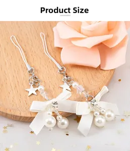 Détail d'un porte-clés perle et nœud avec étoiles argentées sur tulle blanc