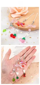 Détail de breloques fraises et cerises en résine avec nœuds roses et perles colorées