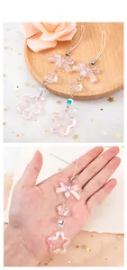 Detailed macro view of pink acrylic bow and star charms with pearlescent beads chain
