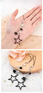 Close-up of black star beaded keychain with silver charms and white pearl on lace mesh