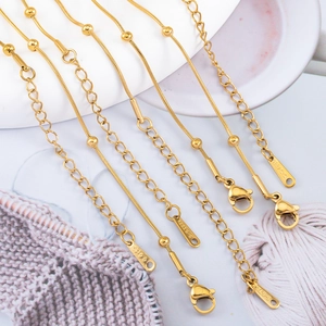 Close-up of golden stainless steel beaded snake chains with S.STEEL engraved tags