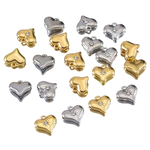 Golden and silver heart pendants with zircon stones and radial texture on white background