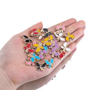 Colorful butterfly alloy charms for DIY jewelry making held in hand over white background