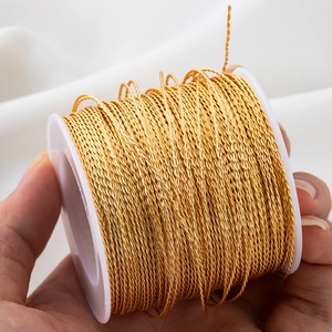 Golden twisted metallic thread for DIY jewelry and tassel making on a white spool