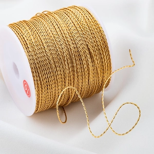 Twisted gold metallic wire for DIY jewelry making on white spool with silk background