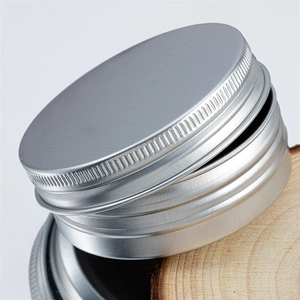 Detail macro shot of a matte silver 40ml aluminum tin container on a wood base