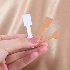 Brown and white kraft paper jewelry price tags for rings and bracelets held in hand