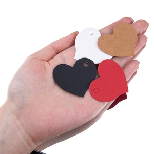 Hand holding assorted small heart-shaped gift tags in red, black, white, and kraft paper