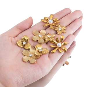 Ciondolo floreale vintage dorato con perle e strass presentato sul palmo della mano