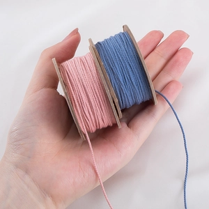 Handheld 1.0mm Tibetan cotton cords in pink and blue wound on wooden spools