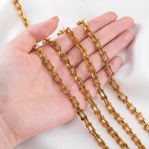 Golden stainless steel chain with architectural I-beam link design on white silk background