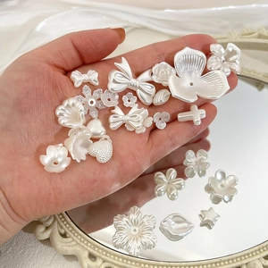 DIY pearl white resin charms in various shapes like flowers and bows on a mirror surface