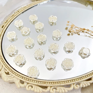 Ivory white resin rose beads for DIY jewelry making on reflective mirror surface