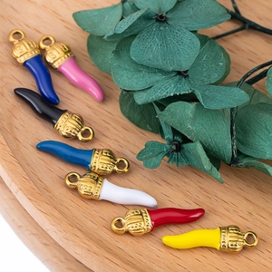 Colorful stainless steel chili pepper pendants with gold caps on a wooden tray