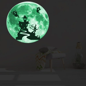 Close-up of glowing green moon wall sticker with ghost castle silhouette in dark room