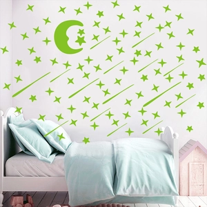 Luminous green moon and stars wall stickers glowing in a cozy bedroom setting