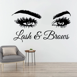Detail eines Lash & Brows Wandtattoos über einem grauen Sessel mit minimalistischer Deko