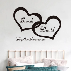 Custom vinyl wall decal with intertwined hearts and names above a bed in a master bedroom