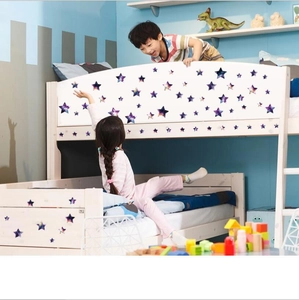 Star-shaped wall stickers with galaxy patterns on a white wooden bed in a kids' room