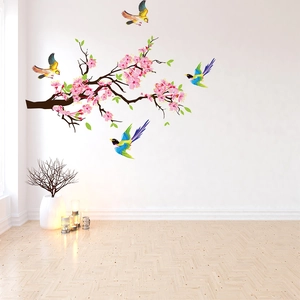 Close-up of pink cherry blossom wall decal and colorful birds on a minimalist white wall