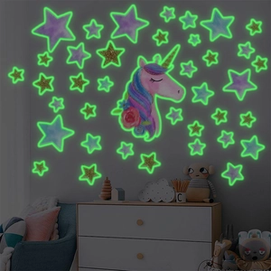 Luminous unicorn and golden stars wall decal set glowing green in a cozy kid's bedroom