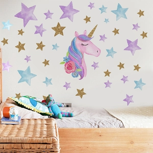 Detail of pink watercolor unicorn and gold star wall stickers in a cozy bedroom setting
