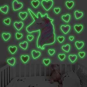 Luminous gold unicorn and heart wall stickers glowing green in a dark bedroom