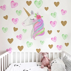 Close-up of watercolor unicorn wall stickers with gold hearts in a cozy nursery setting