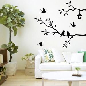 Modern wall decal with birds on branches and hanging birdhouse in a living room setup