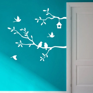 White tree branch wall decal with birds and birdhouse on a blue interior wall background