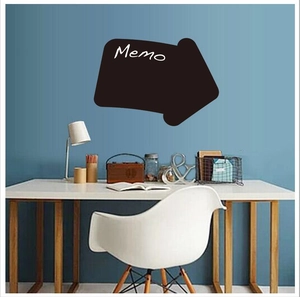Arrow-shaped blackboard memo sticker on a blue wall above a white office desk setup