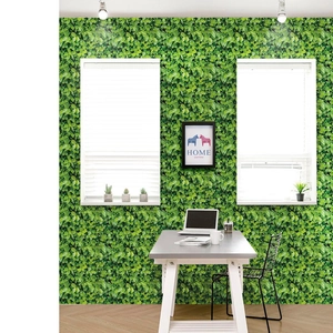 Macro detail of self-adhesive wallpaper featuring dense green leaf patterns in a room