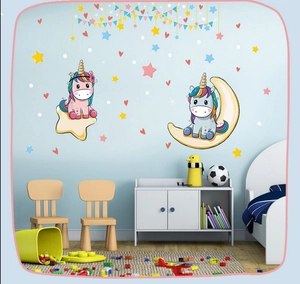 Nursery wall decals featuring cartoon unicorns sitting on stars and moon on a blue wall