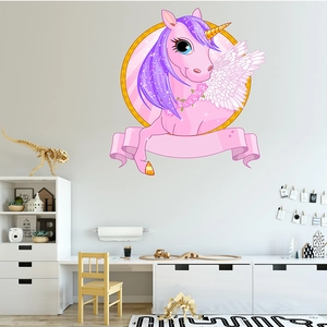 Pink cartoon unicorn wall decal with golden wings and floral wreath on a white wall