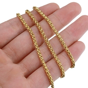 Polished gold stainless steel spiga wheat chain necklace held by hand on white background