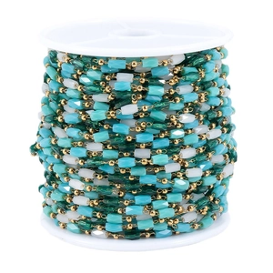 Bunte Perlenkette mit blaugrünen und cremefarbenen Perlen auf einer Spule für DIY-Schmuck