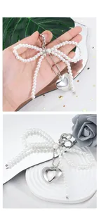 Detail of pearl bow and silver heart charm keychain with an elegant metallic lobster clasp