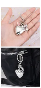 Polished silver heart keychain with bow and flower clasp shown on a black backpack