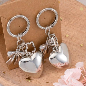 Silver mirror heart pendants with bow and flower charms on a brown gift card display