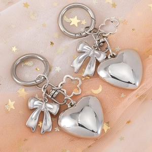 Polished silver 3D heart and bow keychain pendant set on a delicate star mesh background