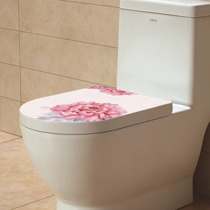 Close-up of pink peony floral stickers on a white toilet lid for bathroom decoration