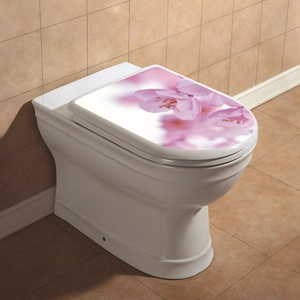 Close-up of pink cherry blossom decal on white ceramic toilet lid with bathroom tile background