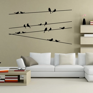 Minimalist birds on wire wall stickers decorating a living room above a white sofa