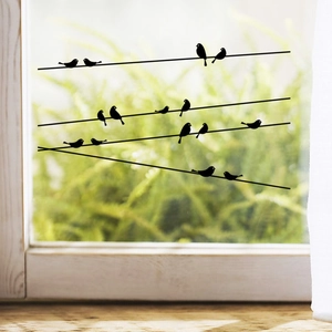 Detail view of black bird silhouettes on power lines wall decals on a glass window