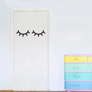 Close-up of black eyelash wall decals applied on a white wooden door in a nursery room