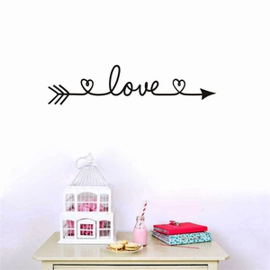 Sticker mural artistique flèche love noir posé dans un salon au décor cosy