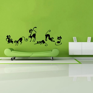 Détail de 6 stickers muraux de chats noirs sur un mur de salon moderne et vert