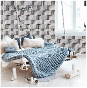 Close-up of blue-grey chunky knit blanket with thick cable texture on a swing bed