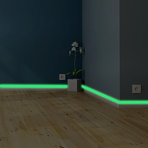 Luminous green glow-in-the-dark safety tape applied to dark wall baseboards for night visibility